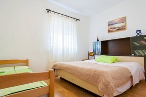 A bedroom with a bed, a wooden chair, a bookshelf, and a window with curtains. - Comfortable house for comfortable stay (14 people) (Šušanj)