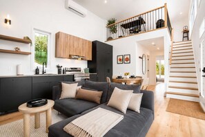 Un espacio habitable moderno con cocina, comedor y una escalera que conduce a un nivel superior.