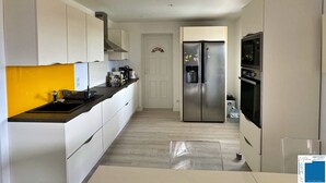 Una cucina moderna con pensili bianchi, un frigorifero in acciaio inox, un forno integrato e un microonde.