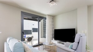 Een moderne woonkamer met een bank, fauteuil en een flatscreen televisie.