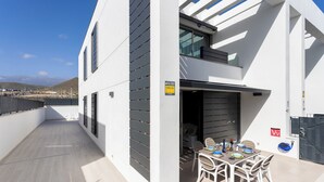 Een modern gebouw met balkon, een eethoek met stoelen en tafel, en uitzicht op het landschap.