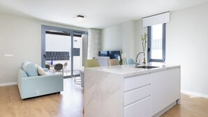 Een moderne keuken met een marmeren eiland, een zithoek met een bank en stoelen, en een groot raam dat voor natuurlijk licht zorgt.
