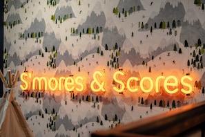 Een muur met een 'S'mores & S'mores' bord en een tent op de voorgrond.