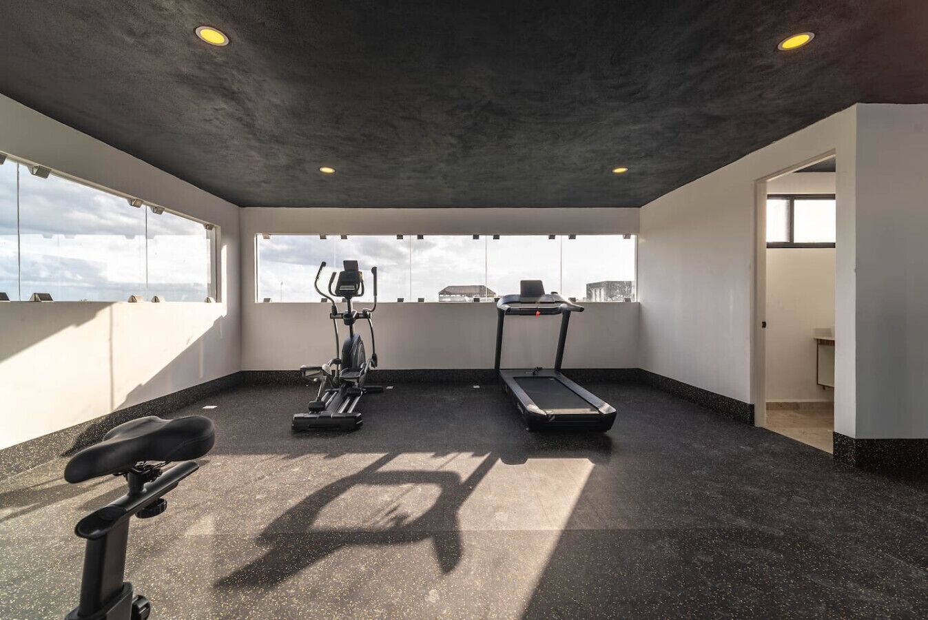 A gym with treadmills, elliptical machines, and a stationary bike.