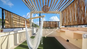 Een terras op het dak met een hangmat, een houten pergola en een zwembad.