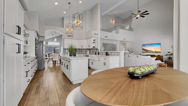 A modern kitchen with white cabinetry, a wooden dining table, and pendant lighting. - Beverly Ocotillo Chandler (Chandler)