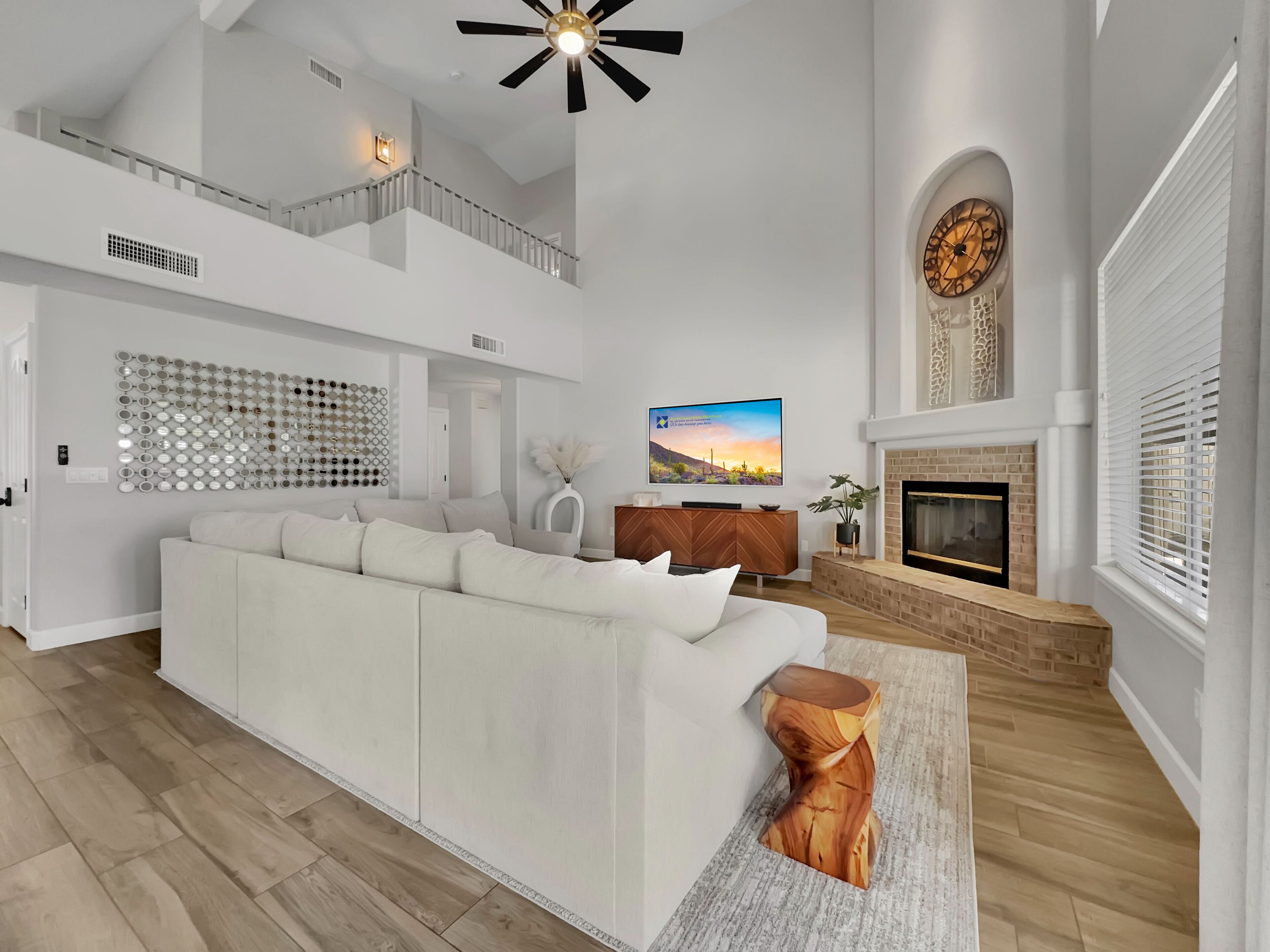 A spacious living room with a high ceiling, a fireplace, and a large TV.