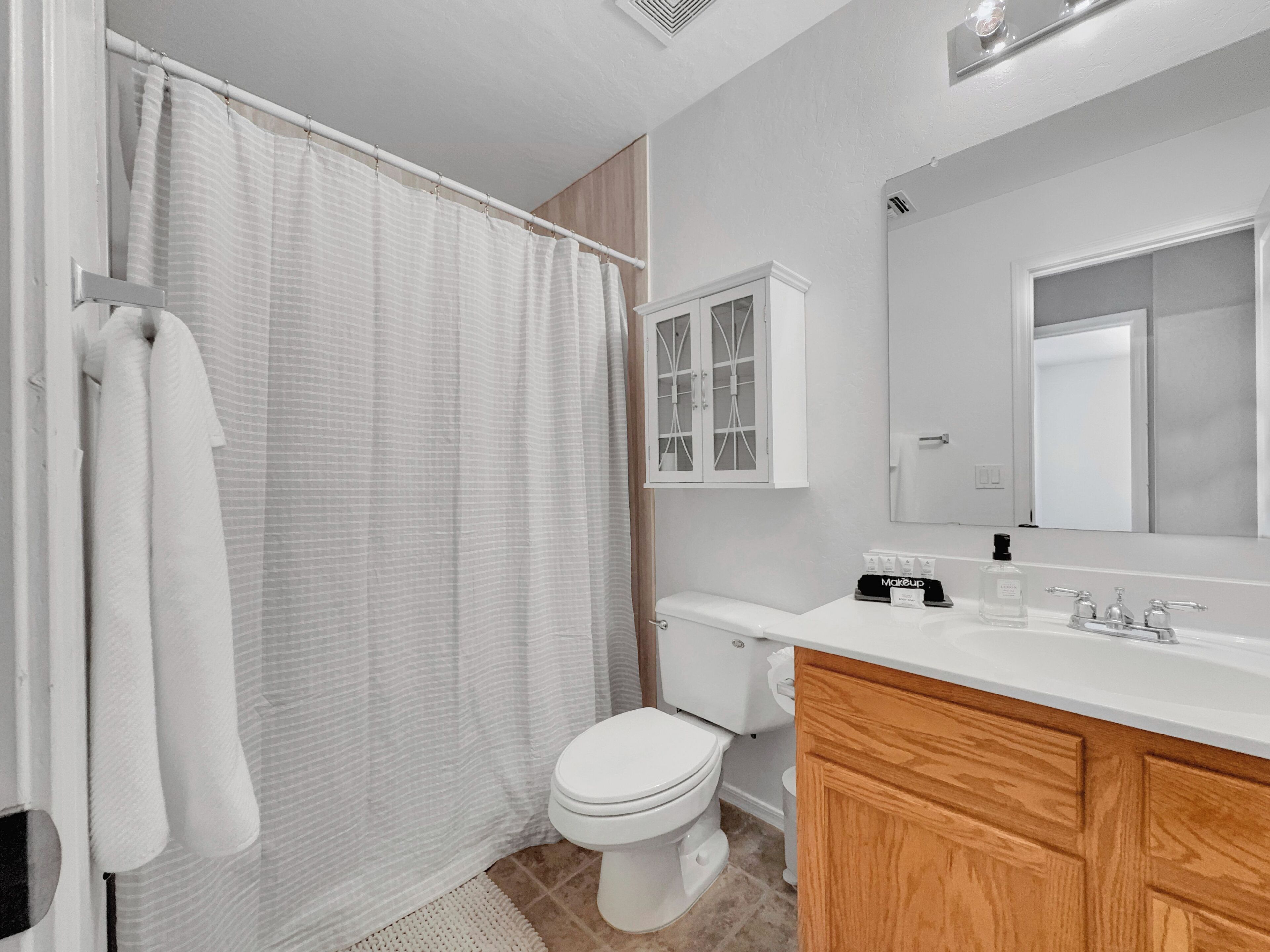 A bathroom with a toilet, a sink, a mirror, and a shower curtain.
