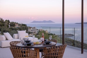 A dining area with a table set for two, overlooking a coastal view. - Anasa Villa Alexandra with Sea View, Wi-Fi and Air Conditioning (Lefkada)