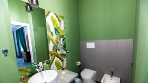 A bathroom with a green wall, a large mirror, a sink, a bidet, and a toilet. - Queen Room with Garden View, Shared Terrace, Wi-Fi and Air Conditioning (Vietri sul Mare)