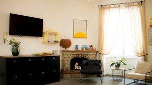 A living room with a TV, fireplace, sofa, and a cabinet with numbered drawers. - Queen Room with Garden View, Shared Terrace, Wi-Fi and Air Conditioning (Vietri sul Mare)
