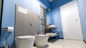 A bathroom with a toilet, bidet, and sink, a blue wall, and a white door. - Superior Triple Room with Shared Terrace, Wi-Fi and Air Conditioning (Vietri sul Mare)