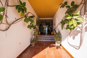 A corridor with potted plants on either side, leading to a door with steps. - Acapulco Apartment 18 by Casasol (Nerja)