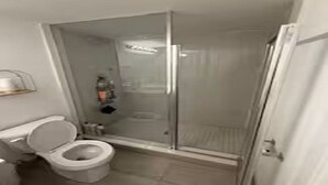 Ein Badezimmer mit Toilette, Duschkabine aus Glas und Waschbecken.