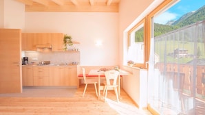 Une cuisine avec des meubles en bois, une table à manger avec des chaises et une grande fenêtre donnant sur un paysage montagneux.