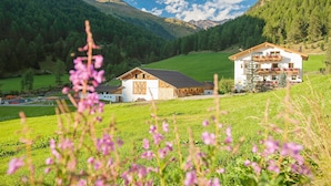 Une maison de campagne avec une grange, entourée de champs verdoyants et de montagnes.