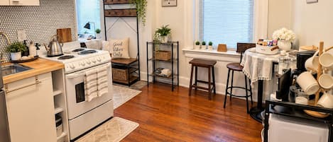 A modern kitchen with white cabinetry, a stove, and a dining area with a table and chairs.