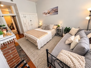 A bedroom with a bed, bedside table, lamp, and a couch. - Heart of OTR -Stadiums, Museums, Nightlife, Casino -Walkable Everywhere Cinci (Cincinnati)