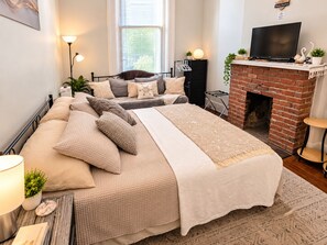 Un dormitorio con cama, chimenea, televisor y ventana con persianas.