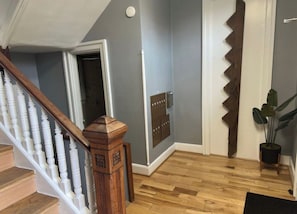 A staircase with wooden balusters, a wooden handrail, and a white door with a zigzag pattern. - Heart of OTR -Stadiums, Museums, Nightlife, Casino -Walkable Everywhere Cinci (Cincinnati)
