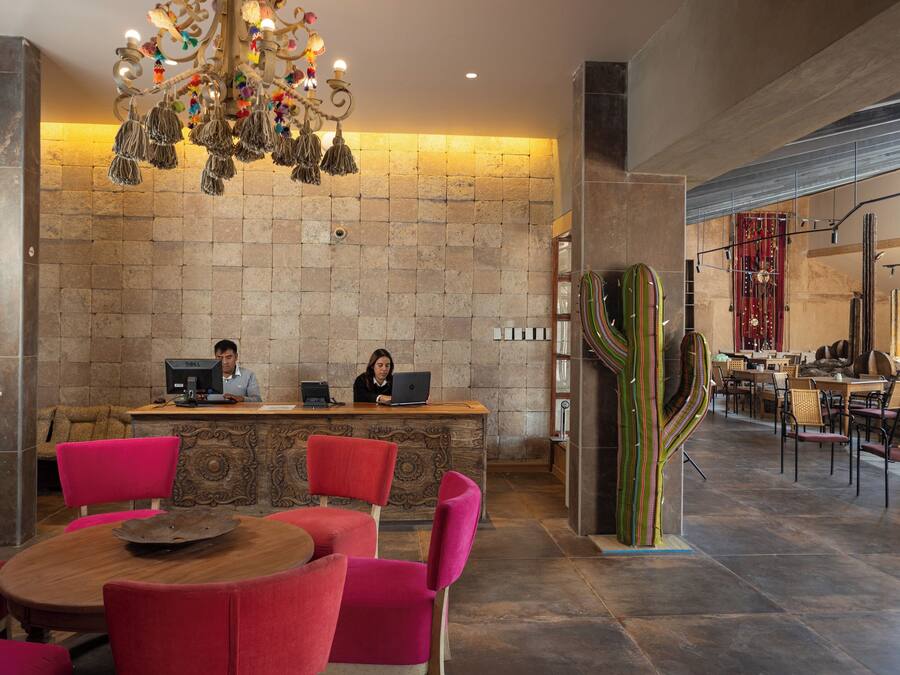 A reception area with a stone wall, a chandelier, and a cactus sculpture. There are two receptionists at desks with computers.