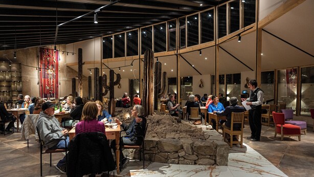 A spacious restaurant with high ceilings and large windows, featuring a rustic stone wall and modern lighting fixtures. - Hotel Rosario Uyuni Collection (Uyuni)