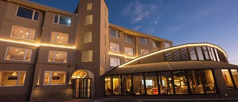 A hotel with a modern design, featuring a central tower, multiple windows, and a covered outdoor area.