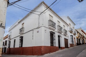 A white building with a red base, multiple balconies, and a clear sky.