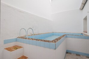 A small, enclosed swimming pool with a blue tiled border and a white interior.