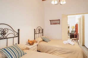 A hotel room with two beds, a nightstand with a vase of flowers, a wooden headboard, and a lamp.