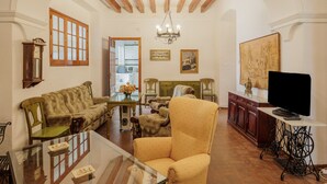 Uma sala de estar com sofá, poltrona e televisão sobre um móvel.
