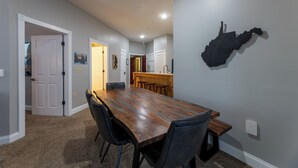 Uma sala de jantar com uma mesa de madeira comprida, cadeiras pretas e um mapa na parede.