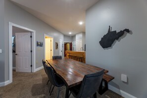 Ein Essbereich mit einem langen Holztisch, schwarzen Stühlen und einer Karte an der Wand.