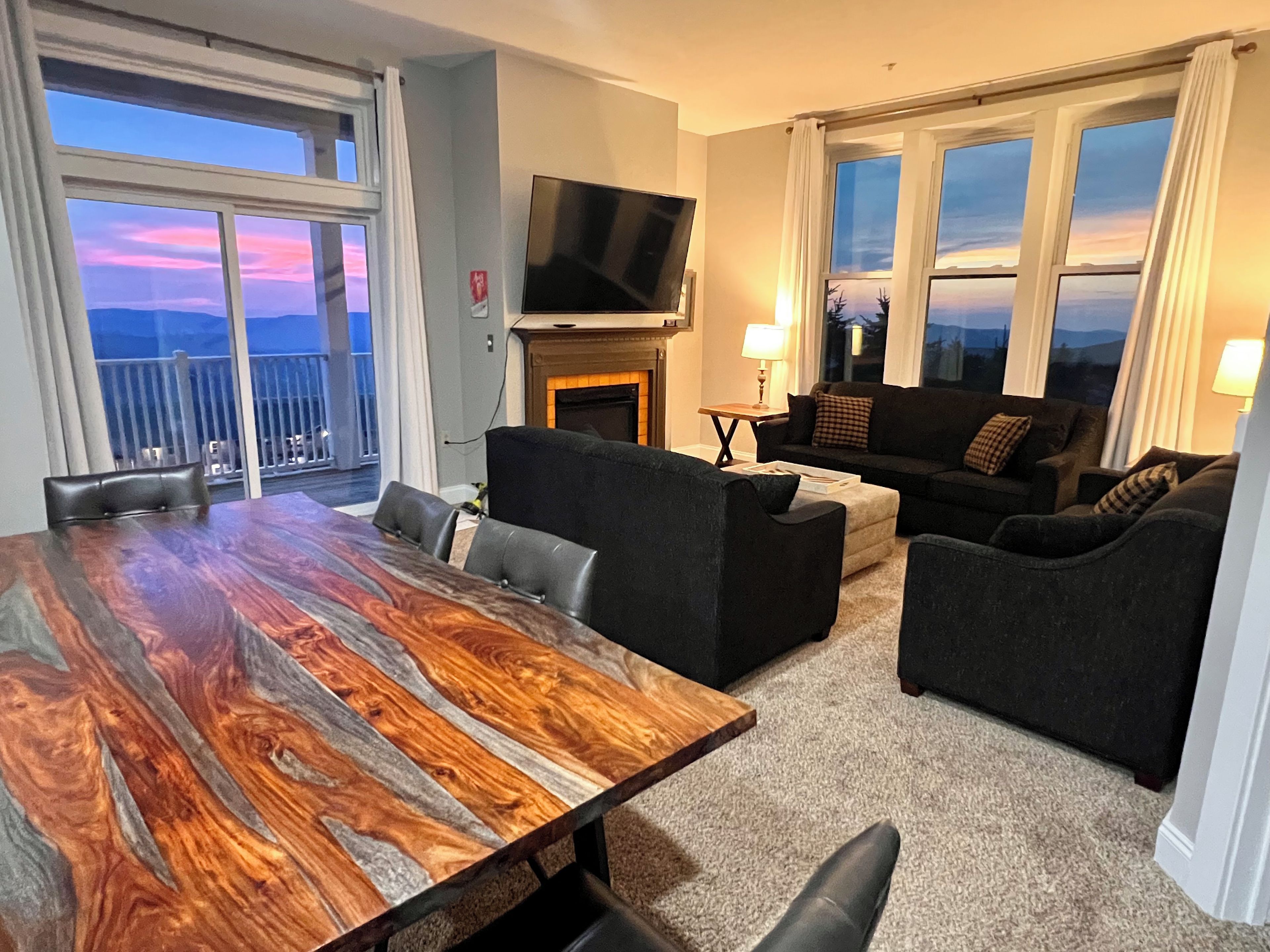 A living room with a large wooden table, two sofas, a TV, and a fireplace.
