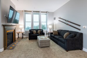 Ein Wohnzimmer mit Kamin, zwei Sofas, einem Fernseher und einem Skiständer.