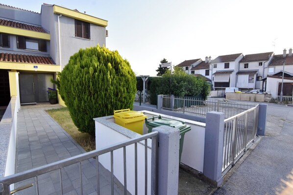 A residential area with houses, a paved walkway, and two trash bins. - Quiet Holiday Apartment With Balcony (Umag)