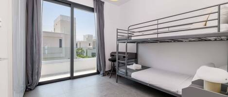 Une chambre d’hôtel moderne avec un lit superposé, un bureau et une grande fenêtre avec des rideaux.