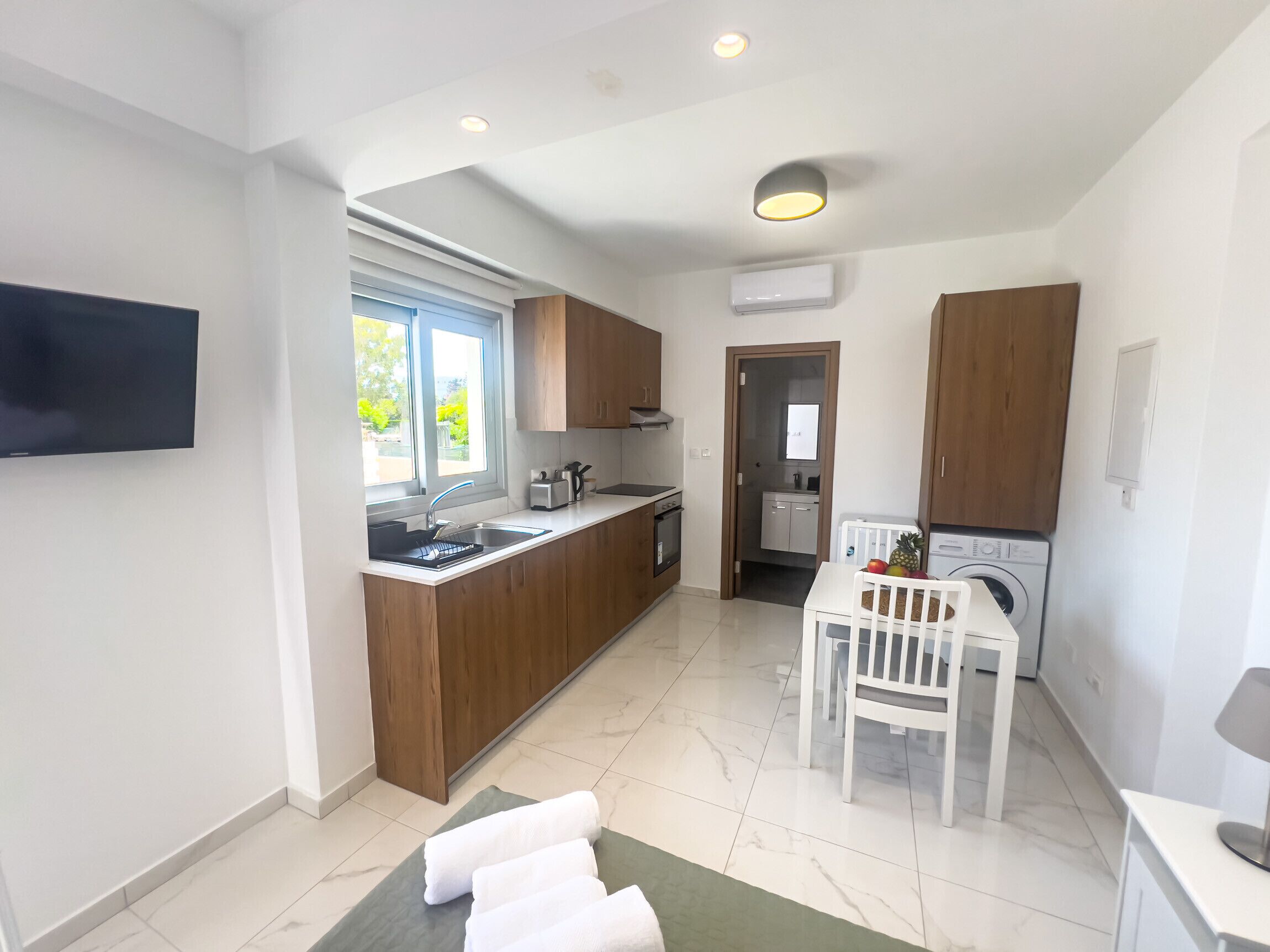 A modern kitchen with wooden cabinets, a built-in oven, and a window providing natural light.