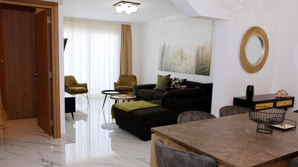 A modern living room with a wooden dining table, two sofas, a coffee table, and a chandelier. - Musan Boutique Inland / Nissi Ave / High-Speed WiFi (Ayia Napa)