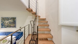 Un escalier avec des marches en bois et des rampes en métal, un canapé bleu et un tableau accroché au mur.