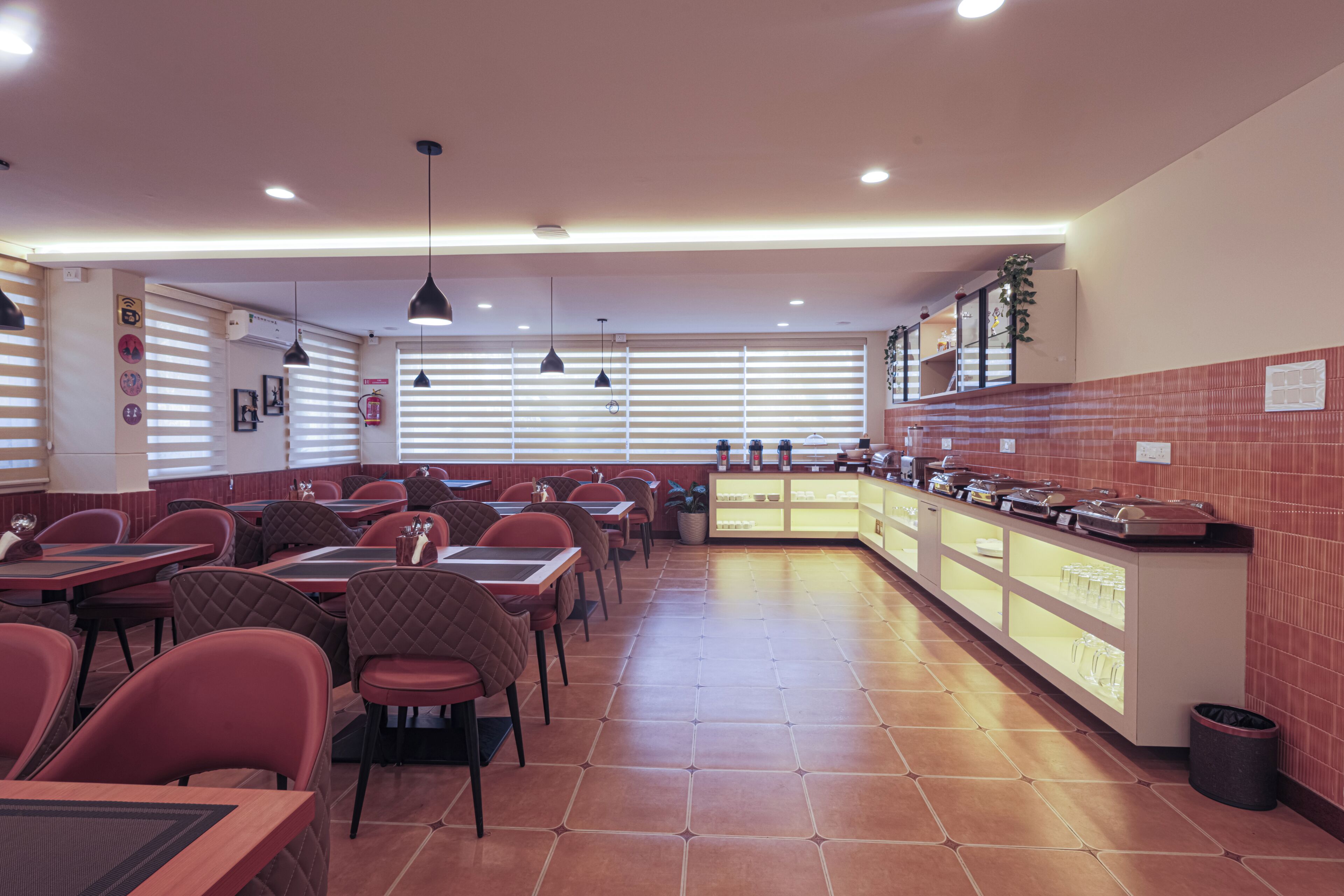 A restaurant with multiple tables and chairs, a counter with food items, and a tiled floor.