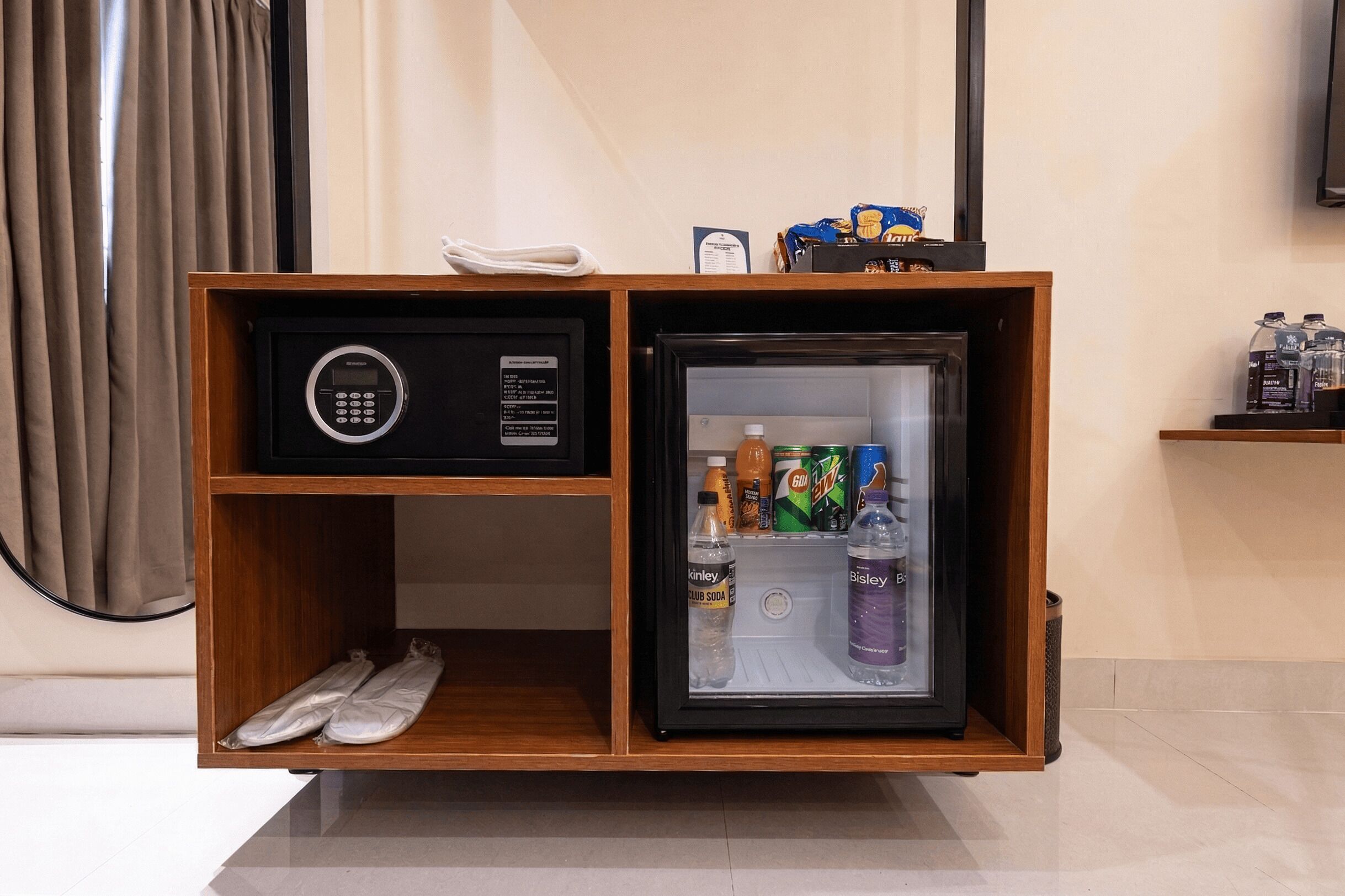 A minibar with a digital lock, a refrigerator with beverages, and a pair of shoes.