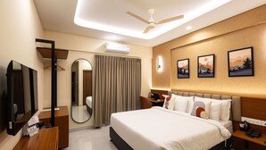 A hotel room with a bed, bedside tables, a desk, a mirror, a ceiling fan, and artwork on the wall. - Felix Inn Boutique Hotel - Manyata Tech Park (Bengaluru)