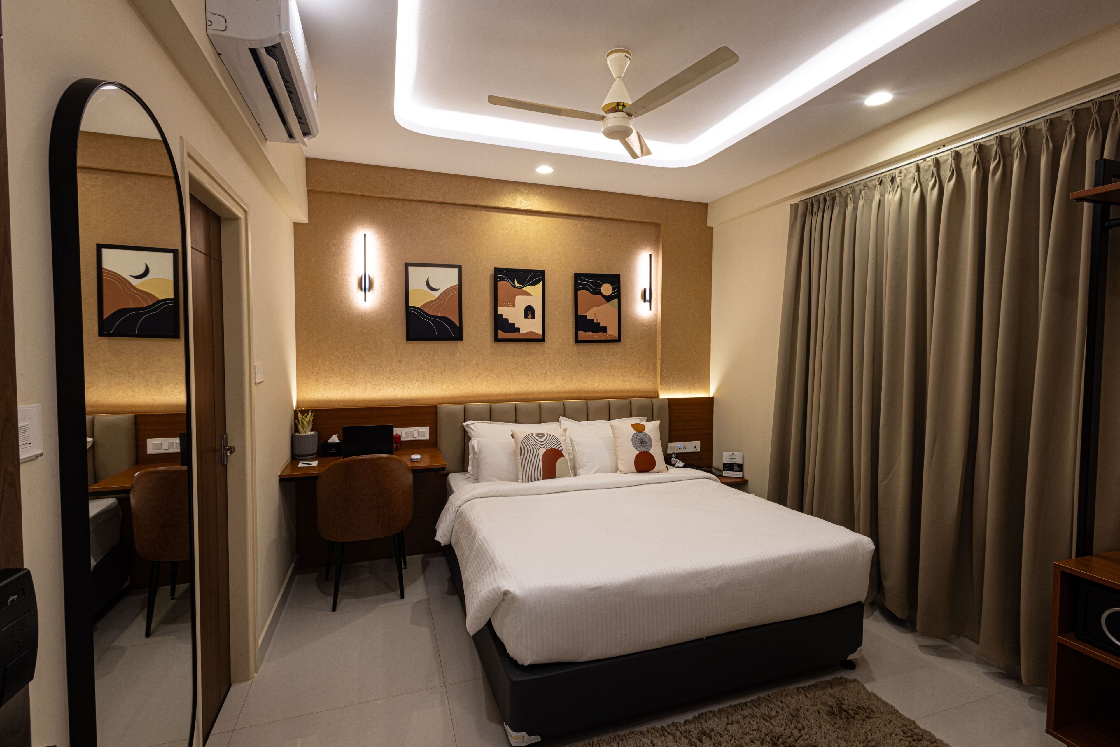 A hotel room with a bed, desk, chair, and a ceiling fan.