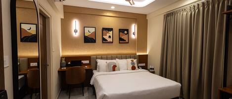 A hotel room with a bed, desk, chair, and a ceiling fan.