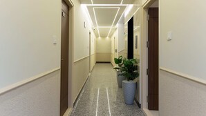 A hotel hallway with a modern design, featuring a straight layout, light-colored walls, and a polished floor. - Felix Inn Boutique Hotel - Manyata Tech Park (Bengaluru)