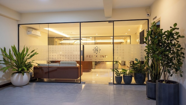 A hotel lobby with a reception desk, seating area, and potted plants. - Felix Inn Boutique Hotel - Manyata Tech Park (Bengaluru)