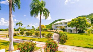Ein Resort mit einem weißen Gebäude, Palmen und einem gepflegten Garten.