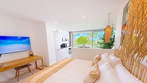 A modern hotel room with a large bed, a desk, a TV, and a view of the outdoors. - La Case à Sucre – Peaceful retreat, sea view, beach front (Anse Marcel)