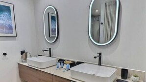 Une salle de bain moderne avec deux lavabos, un grand miroir et un meuble-lavabo en bois.